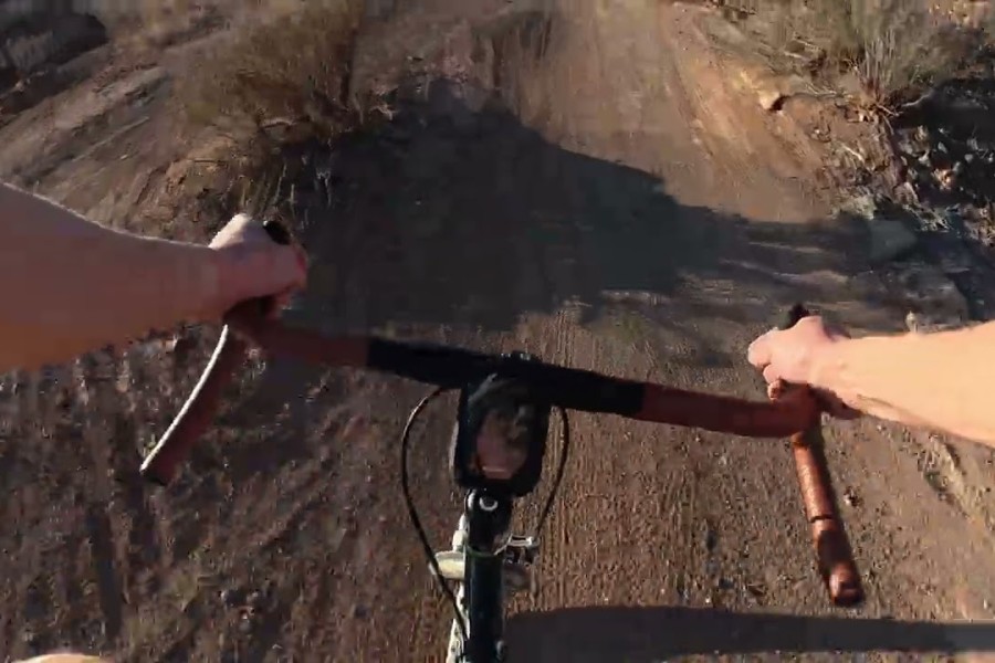 A view of handlebars on a dirt trail.